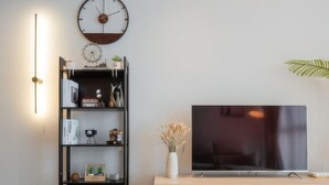 Een moderne woonkamer met een televisie, een boekenkast en een klok aan de muur.