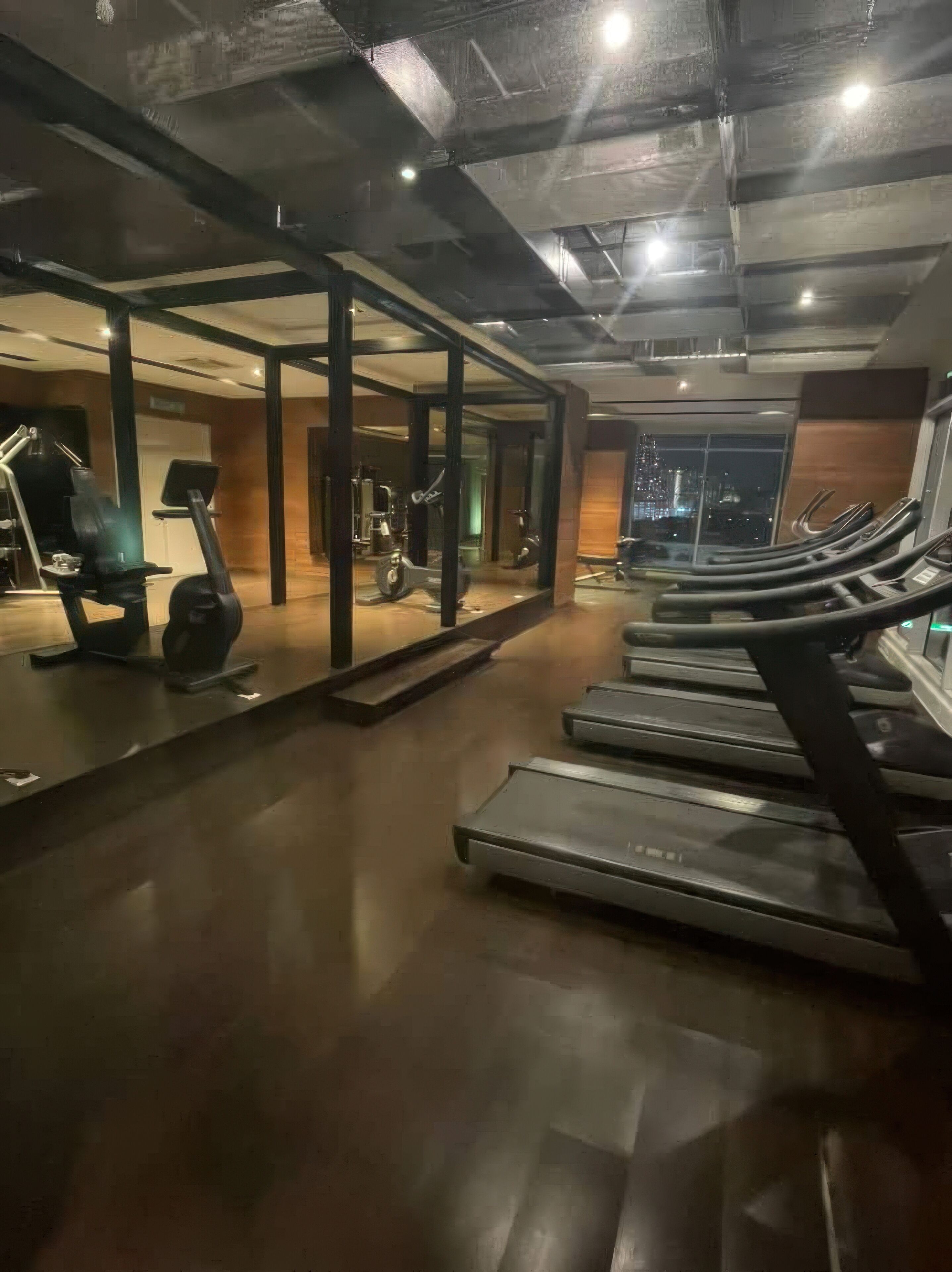 Une salle de sport équipée de tapis de course, de vélos d’exercice et d’appareils de musculation.
