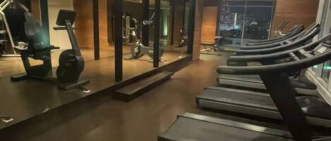 Une salle de sport équipée de tapis de course, de vélos d’exercice et d’appareils de musculation.