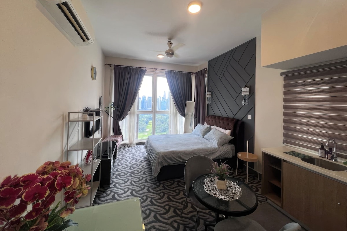 Une chambre d’hôtel avec un lit, un bureau, une chaise, une petite table avec une plante et une fenêtre avec des rideaux.