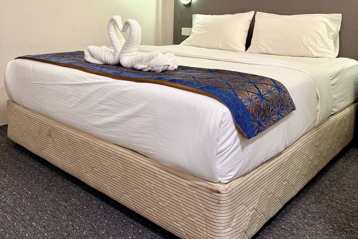 Een hotelkamer met een groot bed, een wandairconditioner, een kunstwerk aan de muur en een bedlampje.