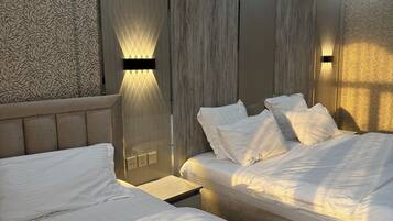 Een moderne slaapkamer met twee bedden, een houten hoofdbord en wandlampen.