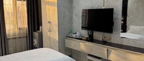 Une chambre d’hôtel avec deux lits, un bureau doté d’un téléviseur à écran plat, un minibar et une grande fenêtre avec des rideaux.