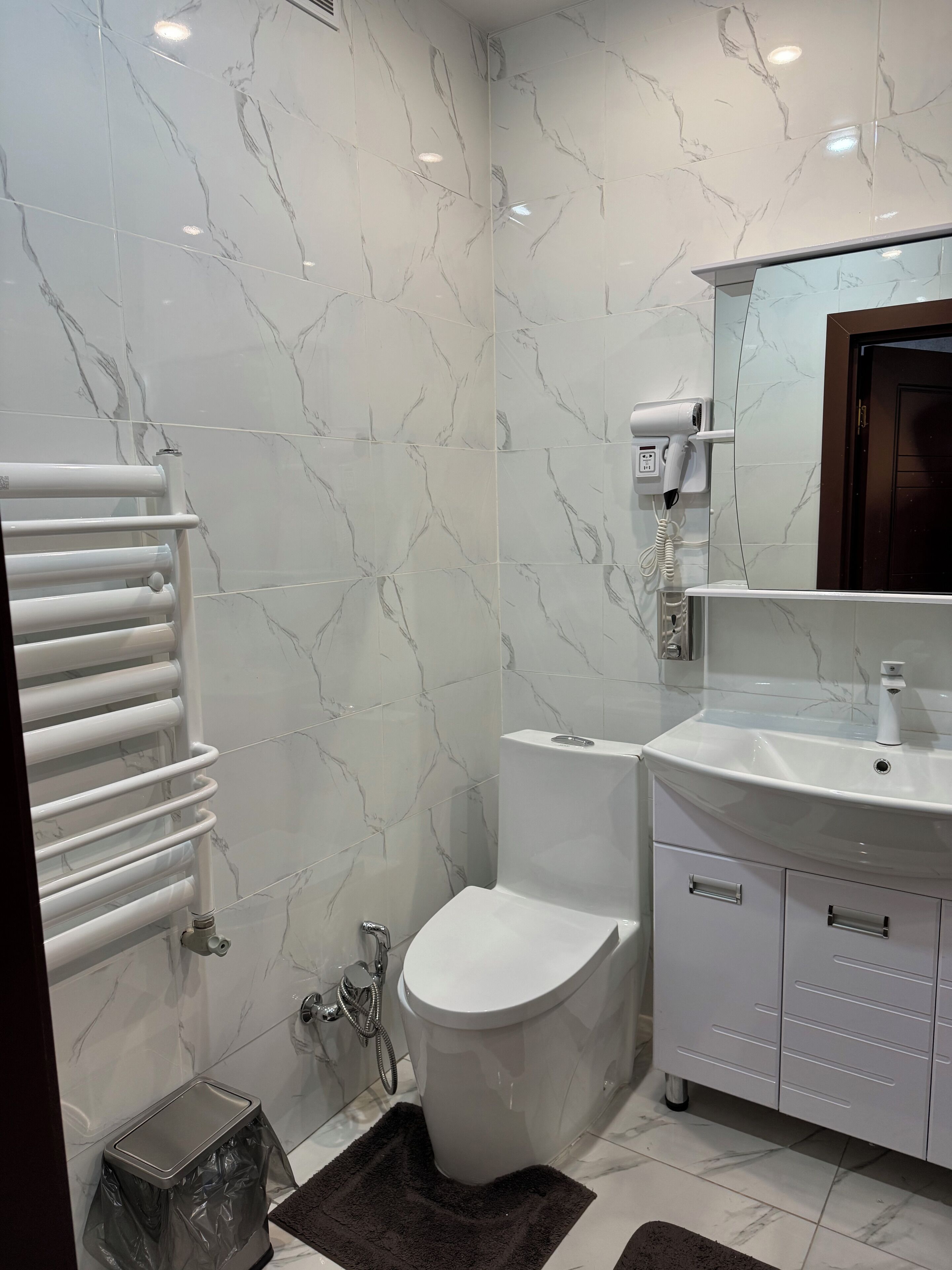 A bathroom with a toilet, sink, and towel rack.