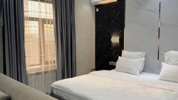 A modern bedroom with a large bed, a sofa, and a marble accent wall.