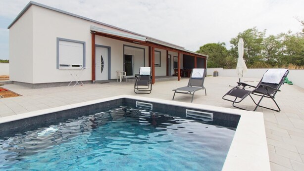 Uma casa moderna com piscina, área de estar externa e um alpendre coberto.