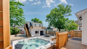 Une terrasse en bois avec un jacuzzi, une petite cuisine extérieure et un espace salon abrité.