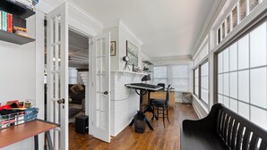 Une pièce avec un plancher en bois, un banc noir, un bureau avec une chaise et une bibliothèque.