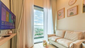 A modern living room with a sofa, a TV, and a window with curtains. - The Grand Subang Jaya SS15 By Emily in Town (Subang Jaya)