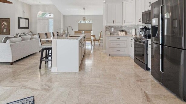 A modern kitchen with white cabinets, stainless steel appliances, and a central island.