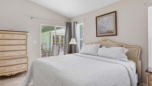A bedroom with a large bed, a dresser, and a painting on the wall.