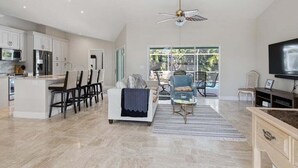 A spacious living area with a kitchen, dining area, and a large window providing natural light.