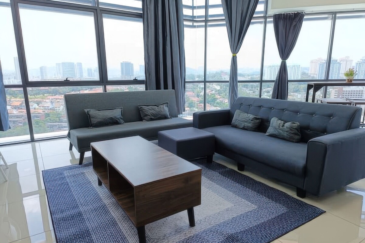 Una sala moderna con un conjunto de sofás, una mesa de centro y vistas de la ciudad a través de amplias ventanas.