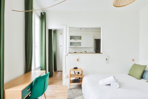 Moderni hotellihuone, jossa on sänky, työpöytä, tuoli, peili ja pieni hylly.