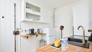 A compact kitchen with a coffee maker, kettle, and water bottles on the counter.