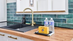A kitchen with a black sink, a gold faucet, and a welcome sign on the counter.