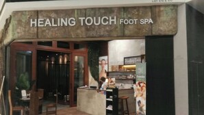 A foot spa named "Healing Touch Foot Spa" with a wooden interior, a reception desk, and a signboard advertising "Healing Taco". - Luxstay Atria Sofo Suites Apartments (Petaling Jaya)