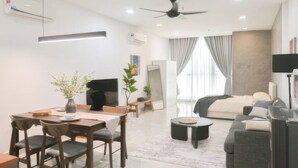 A modern living room with a dining area, a sofa, a TV, and a ceiling fan. - Luxstay Atria Sofo Suites Apartments (Petaling Jaya)