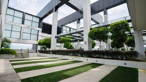 A modern building with a glass facade, concrete pillars, and green landscaping. - Luxstay Atria Sofo Suites Apartments (Petaling Jaya)