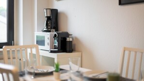 A dining area with a table set for two, a coffee maker, a microwave, and a framed picture on the wall. - Big groups / Families / Exhibition (Duisburg)