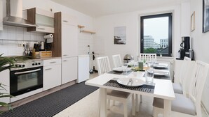 A modern kitchen with white cabinetry, a built-in oven, and a dining area with a table set for two. - Big groups / Families / Exhibition (Duisburg)