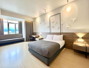 Habitación de hotel moderna con una cama grande, un escritorio y vistas a la ciudad.