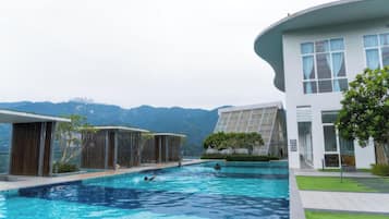 A swimming pool area with modern architecture, a view of mountains, and a well-maintained lawn.