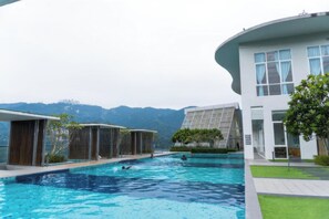Un área de piscina con arquitectura moderna, vistas a montañas y un césped bien cuidado.