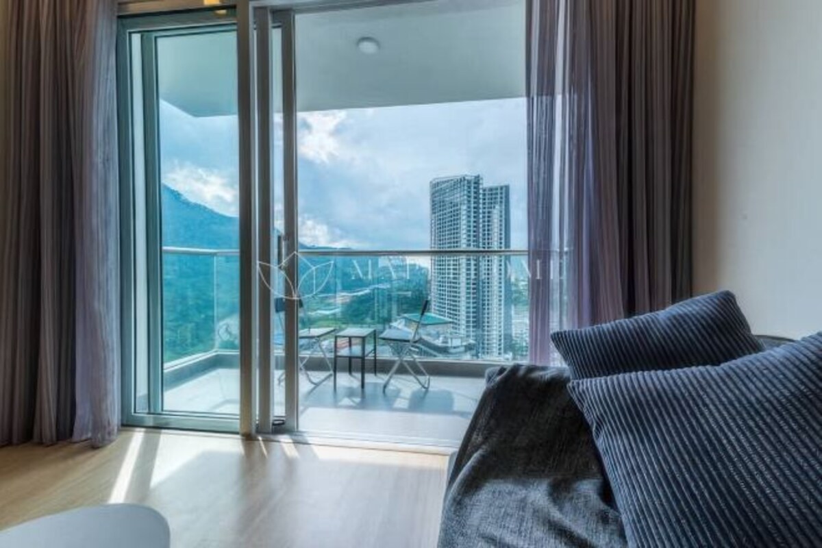Una habitación con balcón, sofá y vista a un paisaje urbano.