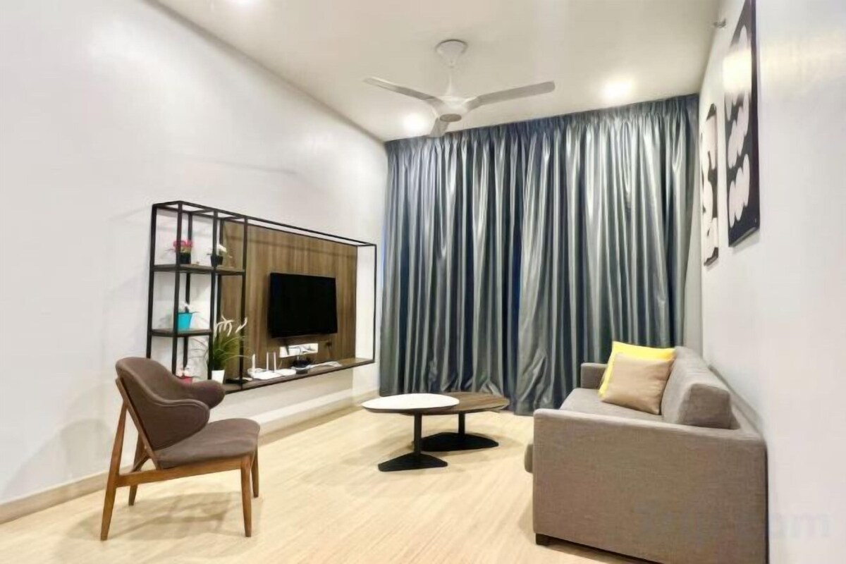 Una sala moderna con sofá, sillón, televisión y ventilador de techo.