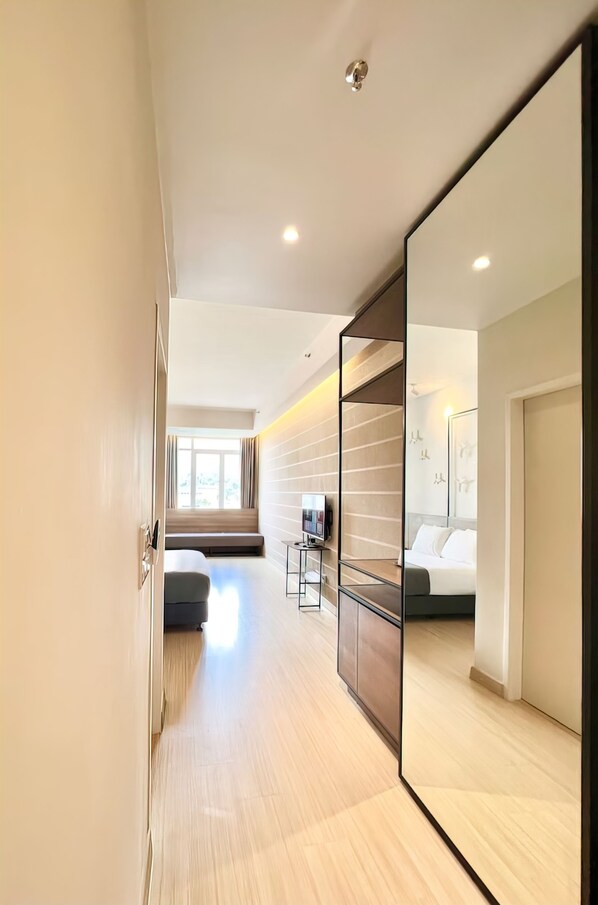 A modern hotel room with a large bed, a seating area with a sofa and a small table, a TV, and a large mirror. - Windmill Upon Hills Retreat Apartments (Genting Highlands)