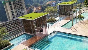 A modern hotel with multiple swimming pools, a covered seating area, and a view of surrounding buildings and hills.