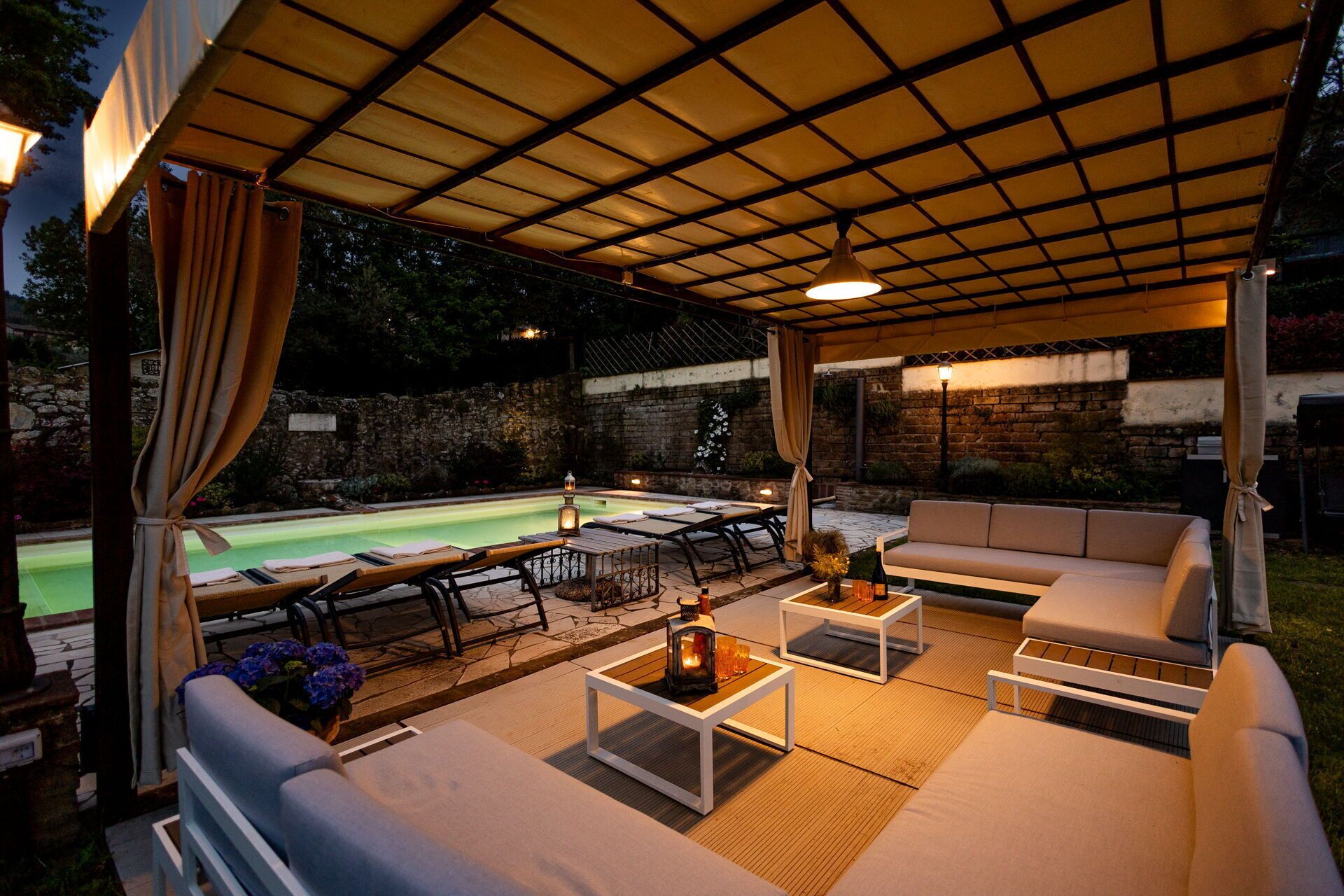 Et overdækket udendørsområde med pool, siddepladser og borde.