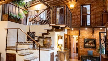Un intérieur spacieux avec un escalier menant à un balcon, une cheminée et un coin repas.