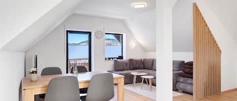 A modern loft with a dining area, a sofa, and a staircase.