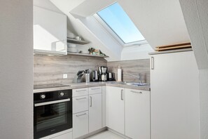 Une cuisine moderne dotée d’une verrière, d’un four encastré et de meubles de rangement blancs.