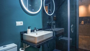 A modern bathroom with a large mirror, a sink, and a glass shower enclosure.