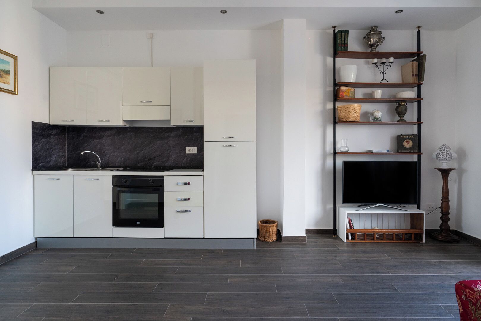 A modern kitchen with white cabinets, a black countertop, and a built-in oven.