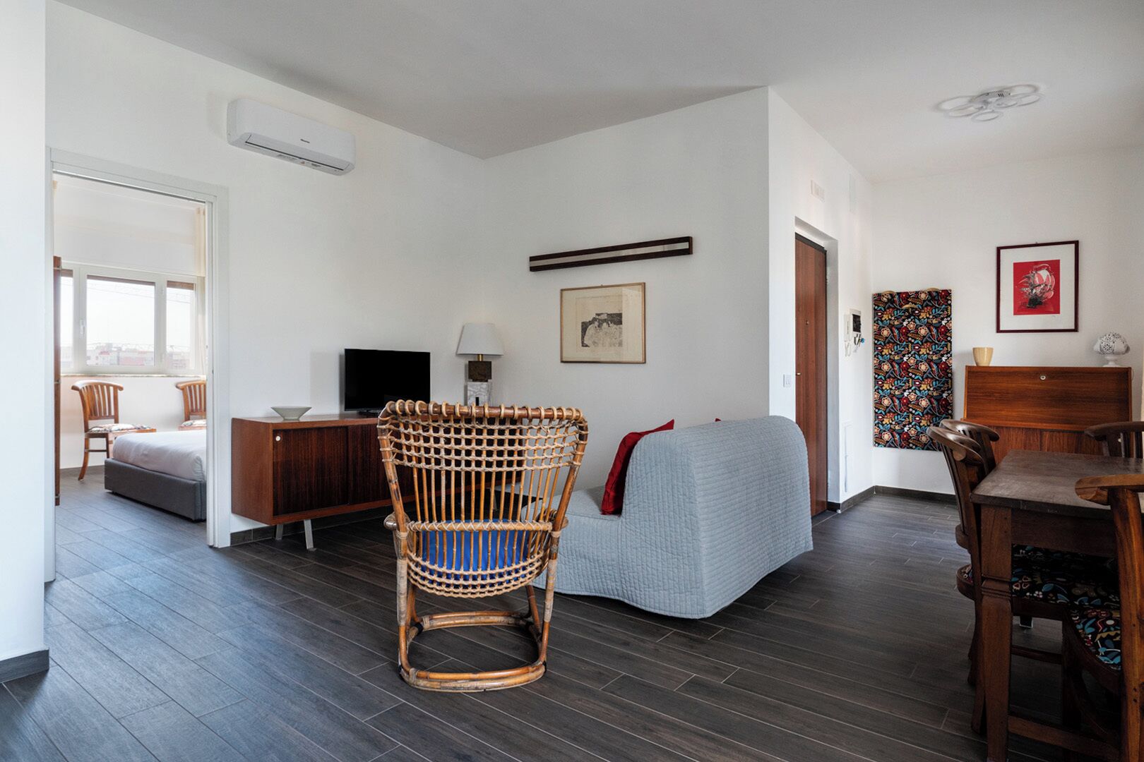 Un salon moderne avec un fauteuil en osier, un canapé, une table à manger et un téléviseur.