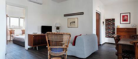 Un salon moderne avec un fauteuil en osier, un canapé, une table à manger et un téléviseur.