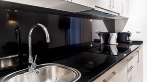A modern kitchen with a stainless steel sink, a black countertop, and white cabinets. - Standard 1 bedroom apartment - Ground floor (Sevilla)