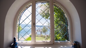 En utbyggnad med stora fönster som vetter mot havet och grönområden.