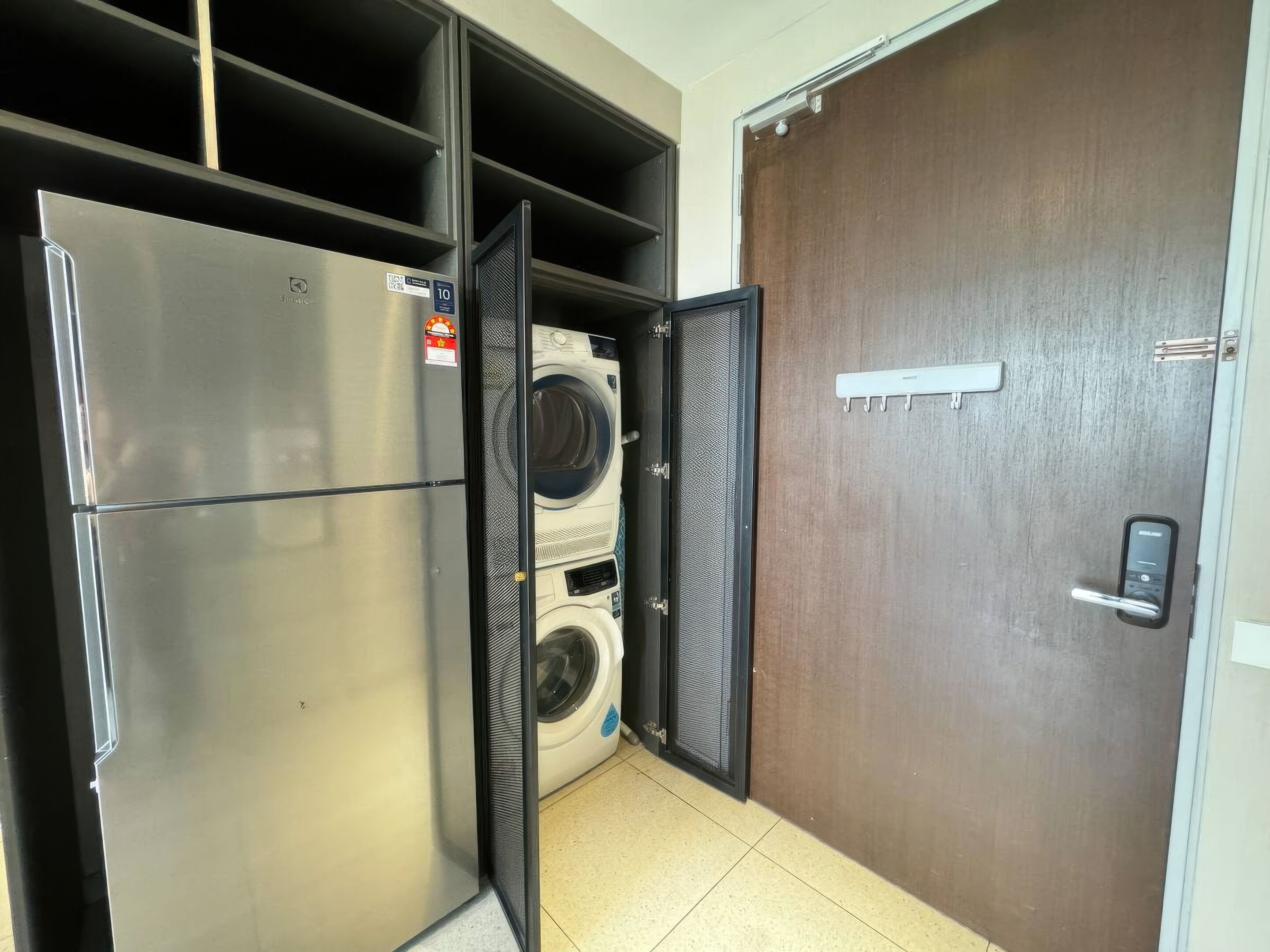 Un lavadero pequeño con un refrigerador de acero inoxidable, una lavadora y una secadora.