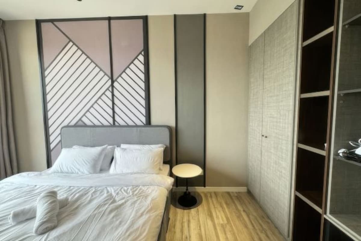 A modern bedroom with a bed, bedside table, and a wardrobe.