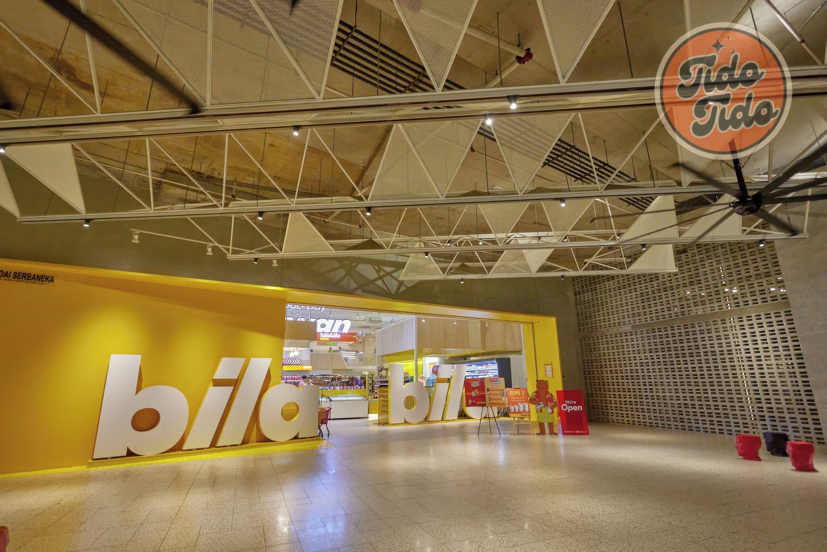 Un interior modern amb una entrada destacada de la botiga 'billa', un sostre amb dibuixos geomètrics i un rètol 'Tide Tido'.
