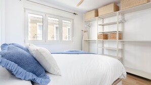 A bedroom with a bed, a ceiling fan, a window, and built-in shelving with baskets. - Apartment 'Bilua' with Wi-Fi and Air Conditioning (Luanco)