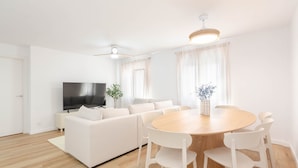 A modern living room with a sofa, a TV, a dining table with chairs, and a plant. - Apartment 'Bilua' with Wi-Fi and Air Conditioning (Luanco)