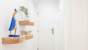 A hallway with a white door, wooden flooring, and floating shelves with decorative items. - Apartment 'Bilua' with Wi-Fi and Air Conditioning (Luanco)