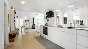 Une cuisine spacieuse avec des meubles blancs, un îlot central et une cuisinière intégrée.