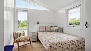Une chambre à coucher avec un lit, une chaise, une lampe et une fenêtre.